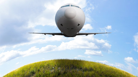 Commercial airplane flying in the sky above the meadow field with cloudscapes background. Travel by airplane conceptの写真素材
