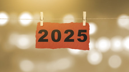 2025 number written on hanging paper with abstract bokeh light background. Happy New Year concept or...
