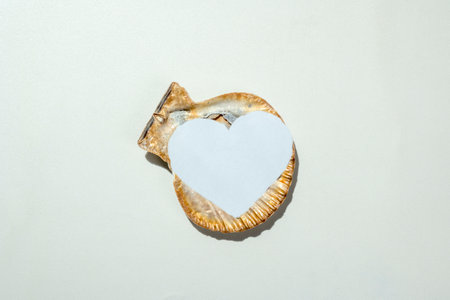 Seashell with white heart on a white background. Copy space. Mockup. Valentine Card. Decoration for...