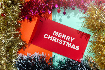 Closeup view of Merry Christmas text on an envelope with a Christmas ornament frame on a colored background. Decoration for Christmas celebrationの写真素材