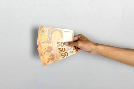 Human hand holding fifty euro banknotes cash on white background. Finance and European currency...