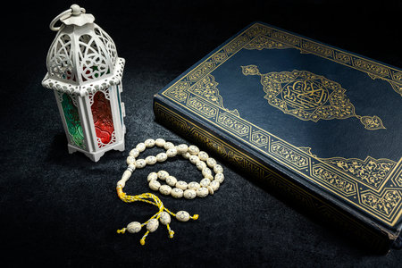 Arabic lantern with prayer beads and the Quran on a black background. Decoration for Muslim holidays celebration. Islamic fasting, Ramadan Kareem, Eid Al Adha, Eid Al Fitr, or Mubarak greetingsの写真素材