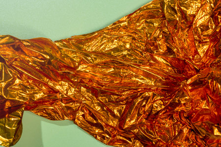 Top view of crumpled golden paper on a colored background. Abstract pattern texture background. Copy space or template. Flat layの写真素材