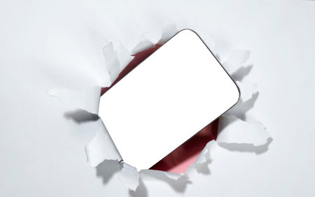 Blank mobile phone from the hole of ripped paper. Mockup or Copy space. Template. Concept of technology or communicationの写真素材