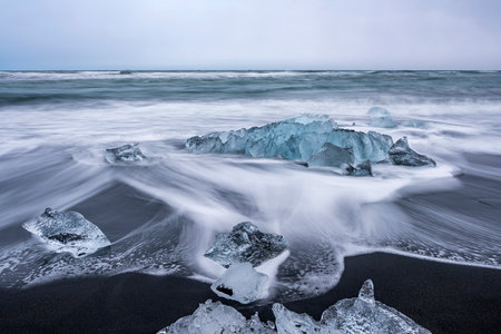 View of the melting glacier on the diamond beach on Jokulsarlon or JÃ¶kulsÃ¡rlÃ³n, Iceland. Nature, travel, climate change, global warming, winter background, or wallpaperの写真素材