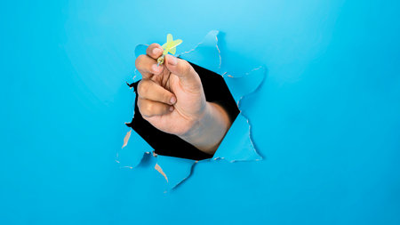 A human hand holding a dart arrow through ripped paper. Mockup or Copy space. Concept of target and challengeの写真素材