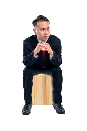 Portrait of an Asian businessman sitting with a serious expression isolated over a white background. Concept of business, entrepreneur, and successfulの写真素材