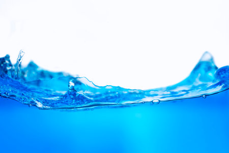 Closeup view of dynamic flowing blue water waves on white background. Liquid splash. Texture and abstract backgroundの写真素材