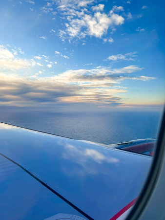 View the airplane wing in clouds with an ocean landscape during a flight in the sky. Nature,...