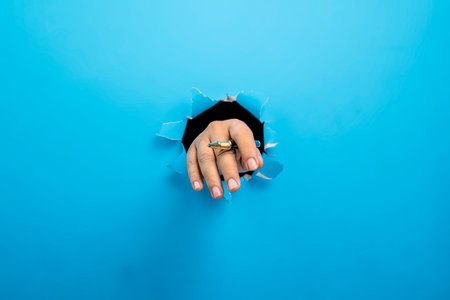 Human hand holding ballpoint pen through ripped paper. Mockup or Copy space. Concept of business, signature, communication, or handwritingの写真素材