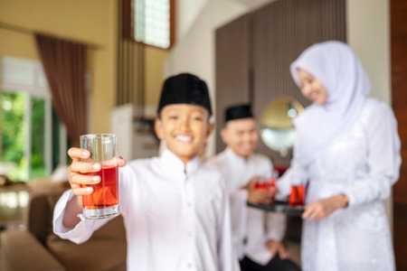Portrait of the Indonesian Muslim boy holding a drink while celebrating Eid Mubarak. Concept of Happy Lebaran, Eid Al Fitr, Idul Fitri, and Ramadan Mubarak celebrationの写真素材