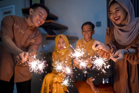 An Indonesian Muslim family playing fireworks in their hometown. Concept of Happy Lebaran, Eid Al Fitr, Idul Fitri, and Ramadan Mubarak celebrationの写真素材