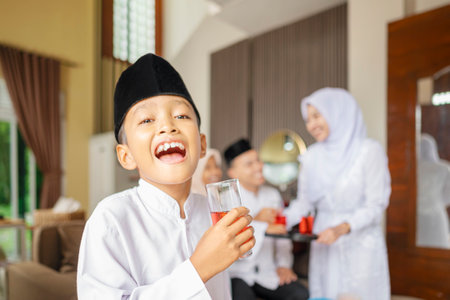 Portrait of the Indonesian Muslim boy holding a drink while celebrating Eid Mubarak. Concept of...