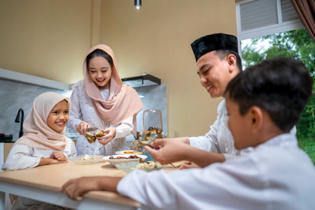 Indonesian Muslim wife serving ketupat rice dumpling for family in the house. Traditional Muslim...