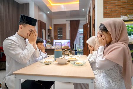 Indonesian Muslim family praying together before eating ketupat rice dumpling. Iftar time. Traditional Muslim food during the celebration of Happy Lebaran, Eid Al Fitr, Idul Fitri, and Ramadan Mubarak celebrationの写真素材