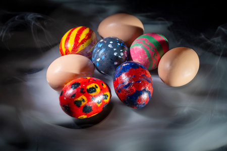 Top view of colorful decorated easter eggs on a dark background. Smoke or fog effect. Concept of...