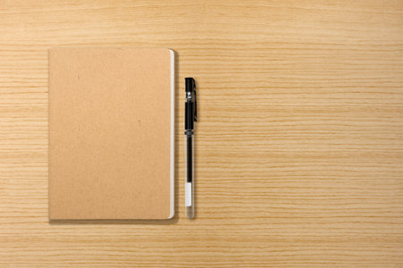 Top view of a notebook and a pen on a wooden background. Blank paper or sheet. Mockup or copy space for your designの写真素材