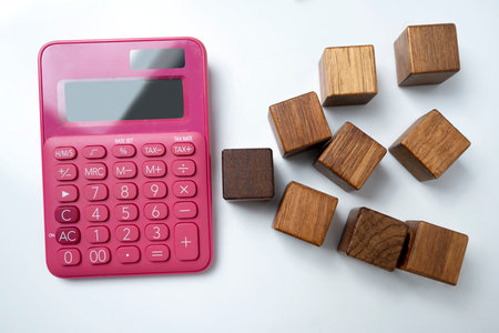 Top view of a pink calculator and wooden cubes on a white background. Mockup or Copy space. Concept of economy and financeの写真素材