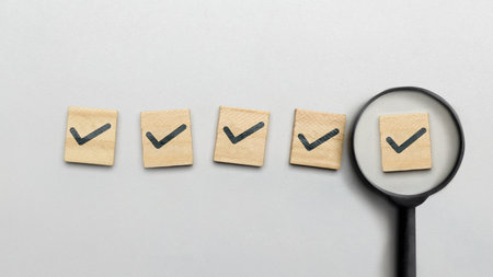 Magnifying glass with checkmark sign on wooden cube on white background. Concept of review, approval, or agreementの写真素材