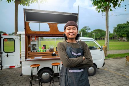 Indonesian southeast asian male barista standing with confidence in front of his coffee shop. A small business of a coffee shop or cafe on a truckの写真素材