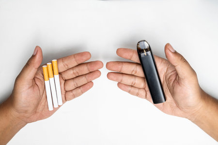 Human hand holding cigarettes, rolled tobacco in paper with a filter tube, and a vape or electronic cigarette are isolated on a white background. No or quit smoking, a bad habit, and unhealthyの写真素材