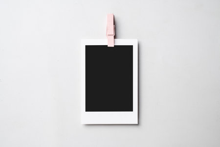 Clothespin with blank polaroid photo paper on a white background. Mockup, template, or copy space. Instant camera photo print frameの写真素材