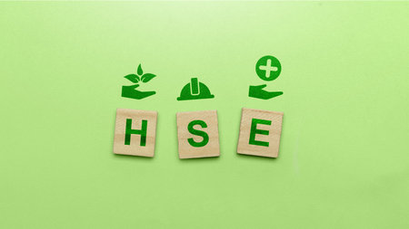 Wooden cubes with HSE sign on green background. Abbreviation of Health, Safety, and Environment. Industry standardization of a safe, healthy, and good environmentの写真素材