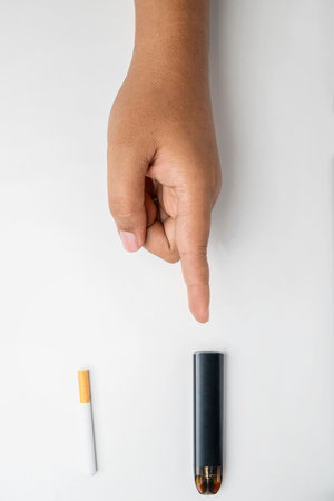 Human hand choose a cigarette, rolled tobacco in paper with a filter tube, or a vape or electronic cigarette are isolated on a white background. No or quit smoking, a bad habit, and unhealthyの写真素材