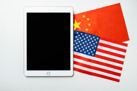 The flags of the USA against China and a tablet with a blank screen. Mockup or copy space. Concept...