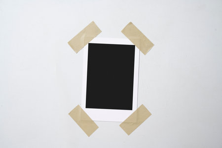 Blank polaroid photo paper stuck with sticky tape on a white background. Mockup, template, or copy...