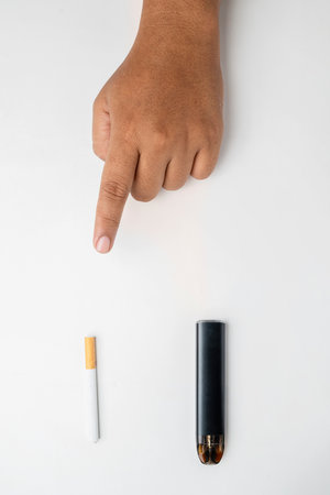 Human hand choose a cigarette, rolled tobacco in paper with a filter tube, or a vape or electronic cigarette are isolated on a white background. No or quit smoking, a bad habit, and unhealthyの写真素材
