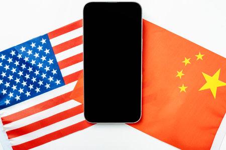 The flags of the USA against China and a cellphone with a blank screen. Mockup or copy space. Concept of the United States of America versus China trade war disputes or economic conflictの写真素材