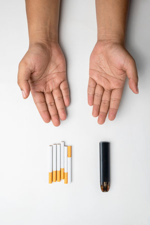 Human hand offering cigarettes, rolled tobacco in paper with a filter tube, and a vape or electronic cigarette are isolated on a white background. No or quit smoking, a bad habit, and unhealthyの写真素材