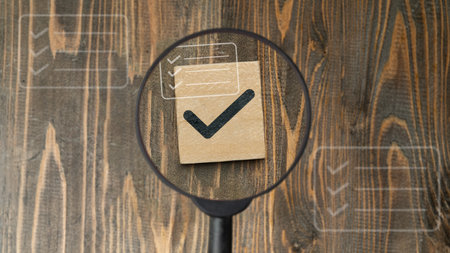 Magnifying glass with checkmark sign on wooden cube with wooden background. Concept of review, approval, or agreementの写真素材