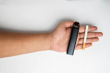 Human hand showing a cigarette, rolled tobacco in paper with a filter tube, and a vape or electronic cigarette are isolated on a white background. No or quit smoking, a bad habit, and unhealthyの写真素材