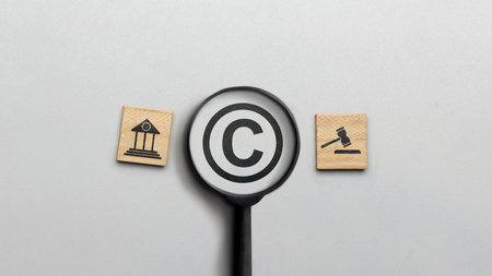 Magnifying glass with copyright logo and icon of law on wooden cubes. Concept of digital copyright and patent, intellectual assets and property, legal protectionの写真素材