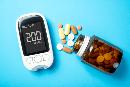 Pills from a container and a glucometer with the glucose level on the screen. Concept of diabetes or a healthy lifestyleの写真素材