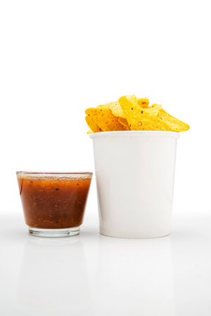 Nachos tortilla chips with salsa barbecue sauce in a glass bowl on a white background. Food and snacks conceptの写真素材