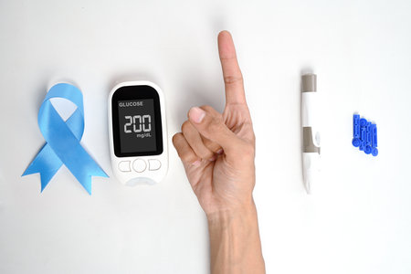 Human hand showing its finger with a kit for checking blood sugar level isolated over a white background. Concept of diabetes or a healthy lifestyleの写真素材