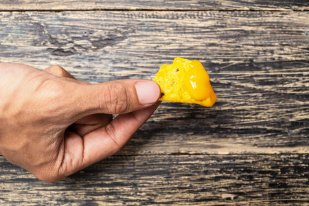 Human hand holding a nachos tortilla chip with cheese sauce on the table. Food and snacks conceptの写真素材