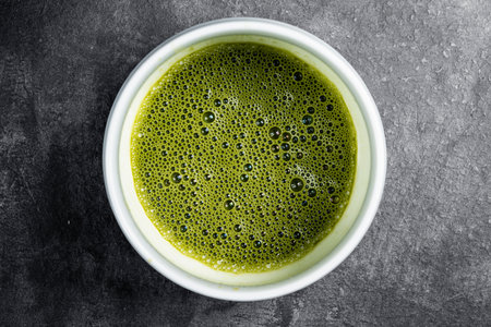 Closeup view of matcha green tea in the bowl on the black table. Top viewの写真素材