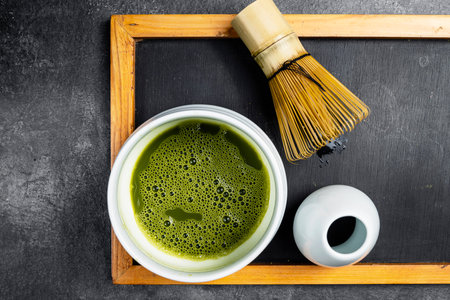 Matcha green tea and a traditional bamboo brush whisk or chasen on a black table. Accessories for making matcha green tea. Top viewの写真素材
