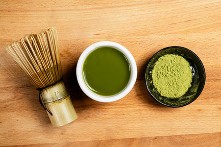 Matcha green tea and a traditional bamboo brush whisk or chasen on a table. Accessories for making...