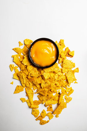 Nachos tortilla chips with cheese sauce in a black bowl on a white background. Food and snacks conceptの写真素材