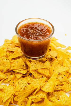 Nachos tortilla chips with salsa barbecue sauce in a glass bowl on a white background. Food and snacks conceptの写真素材