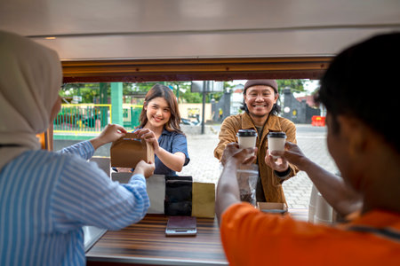 Indonesian southeast asian male and a Chinese muslim female in hijab couple baristas serving drinks...