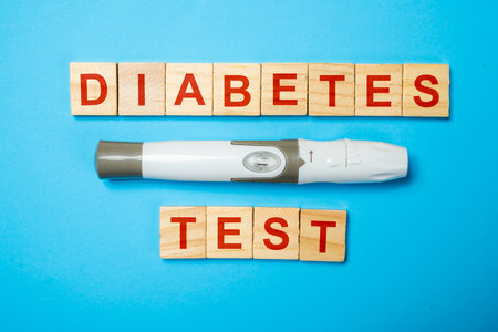 Lancet for checking blood sugar level with text of diabetes test on wooden cubes. Concept of diabetes or a healthy lifestyleの写真素材