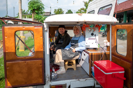 Indonesian southeast asian male and a Chinese muslim female in hijab couple baristas inside the...