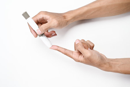 Human hand using a lancet for checking blood sugar level isolated over a white background. Concept...