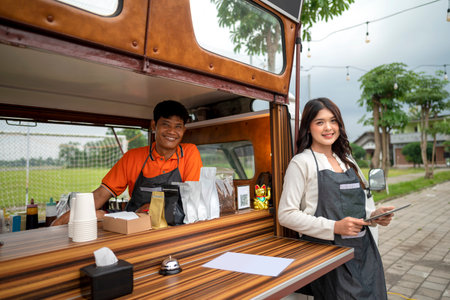 Indonesian southeast asian male with a Chinese female couple barista holding a tablet in their...